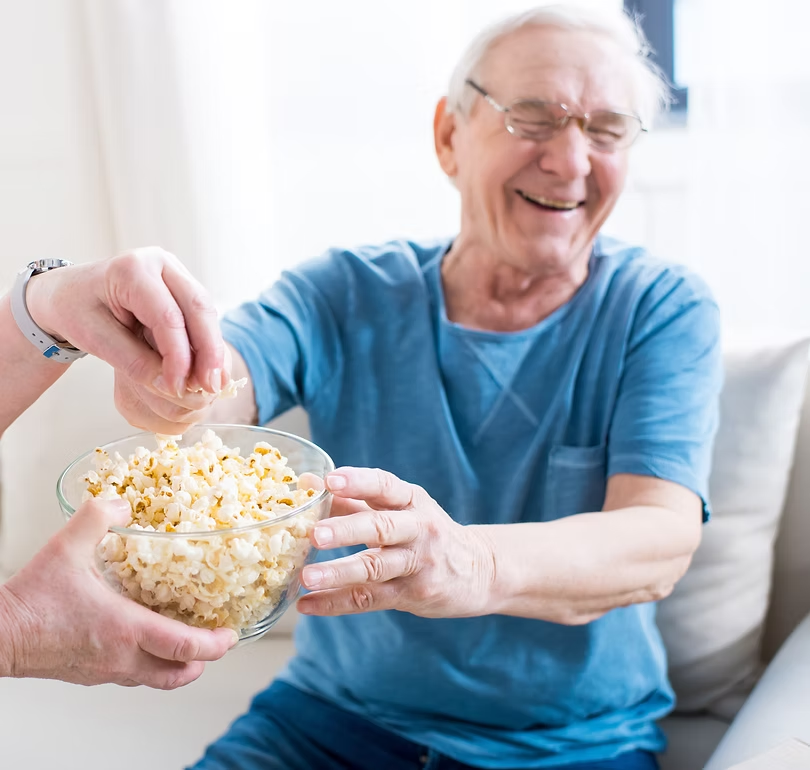 Two people sharing a bowl of popcorn, one laughing.
