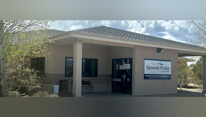 A small building with a sign for "Spanish Peaks Family Clinic" and a few trees around it.