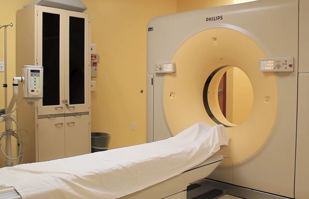 A medical imaging room with a Philips CT scanner and a covered examination table.