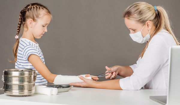 A healthcare professional is adjusting a young girl's arm cast in a medical setting.