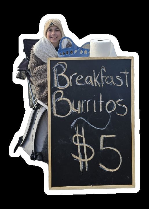 Person selling $5 breakfast burritos, sitting next to a chalkboard sign with paper towels on top.