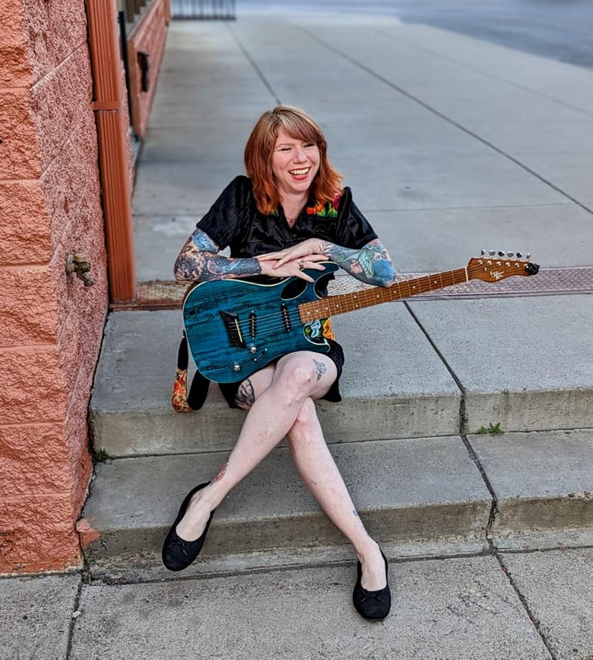May contain: person, sitting, guitar, musical instrument, adult, female, and woman