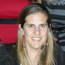 A smiling woman with long hair and earrings, with a red and black background.