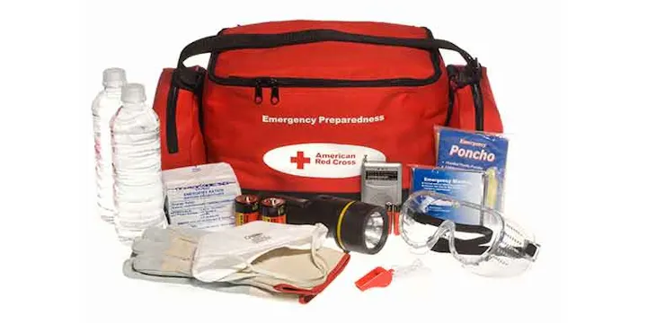 An emergency preparedness kit with water bottles, flashlight, batteries, gloves, first aid supplies, poncho, and goggles.