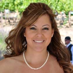 A smiling woman with an updo hairstyle and a pearl necklace.