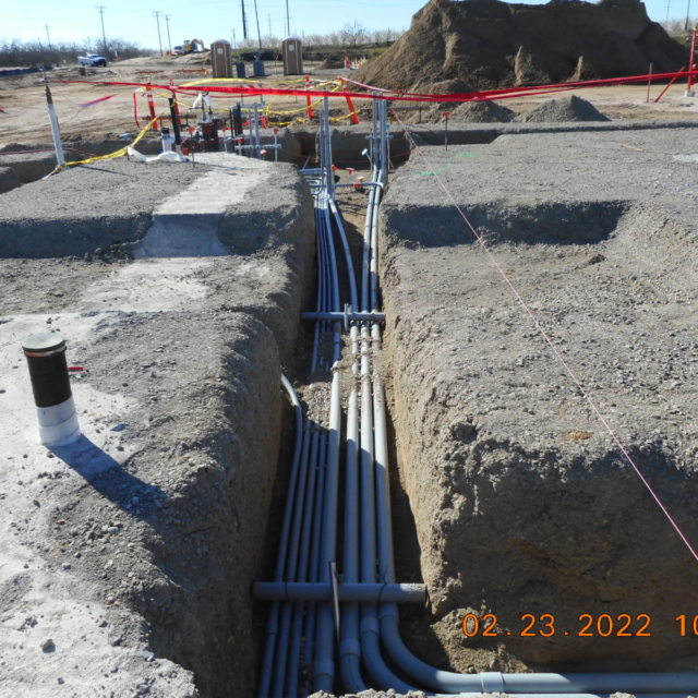Underground pipes in a trench at a construction site with safety barriers.