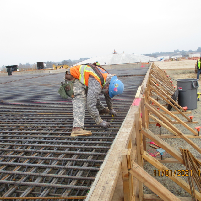 Workers on a construction site with rebar framework for concrete.