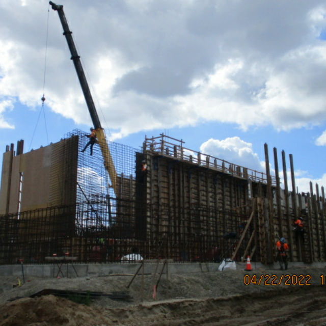 Construction site with crane, workers, and large concrete formwork.
