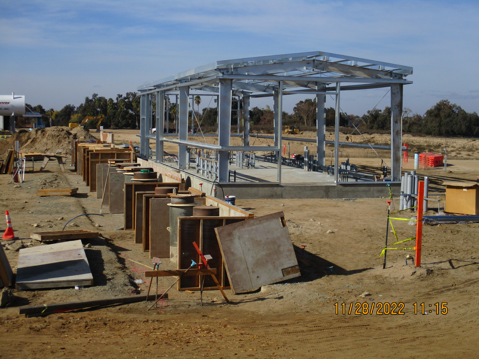 A construction site with a metal frame structure and building materials scattered around.