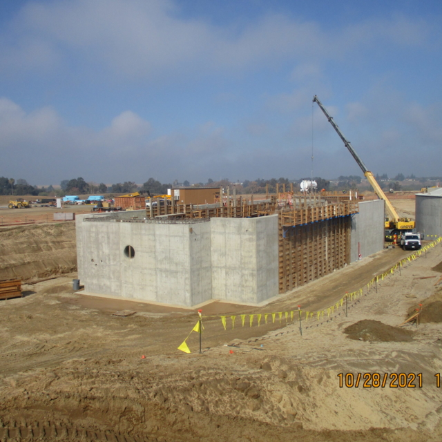A construction site with a concrete structure, crane, and excavation area.