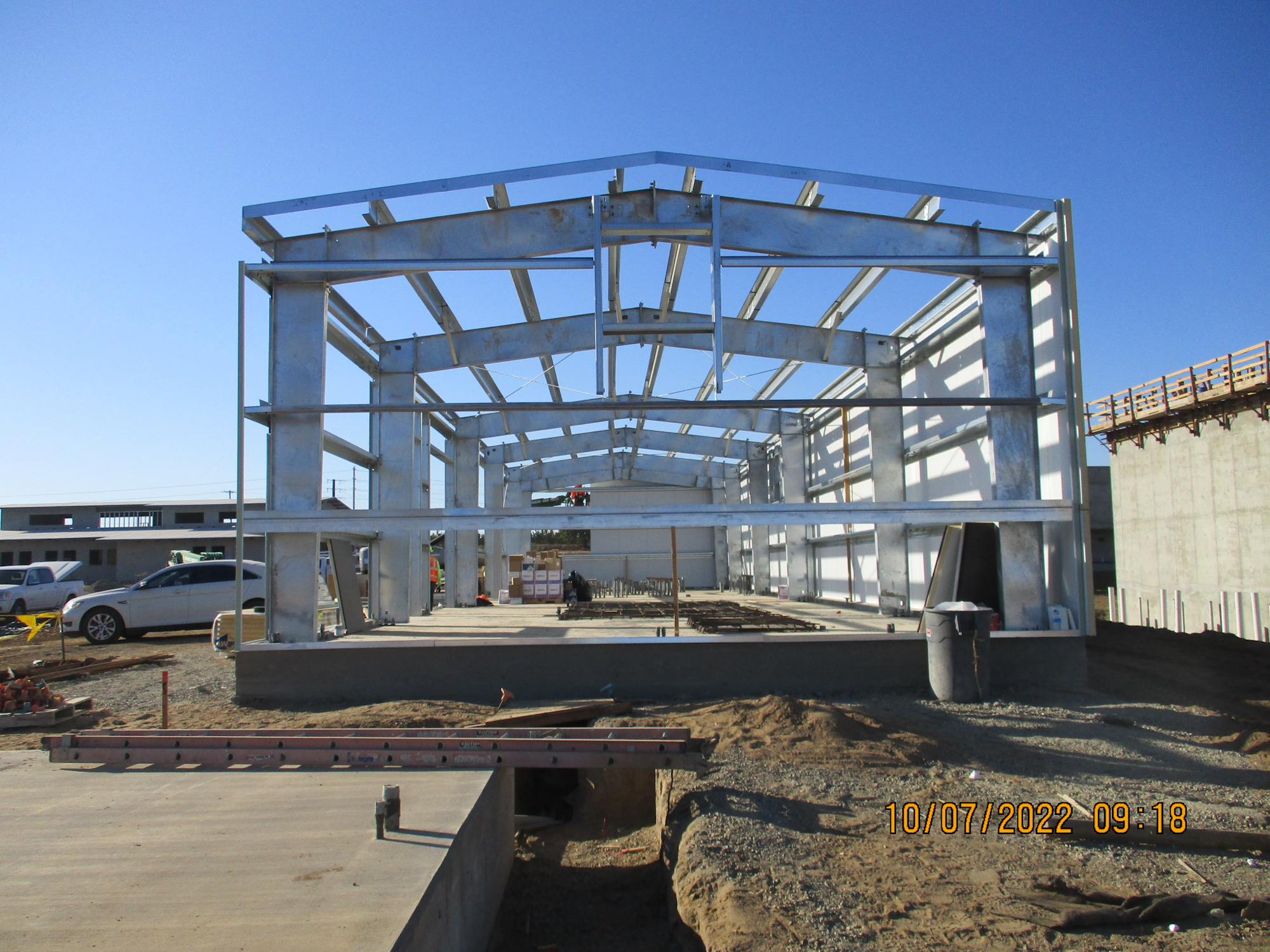 Steel frame structure of a building under construction with clear skies.