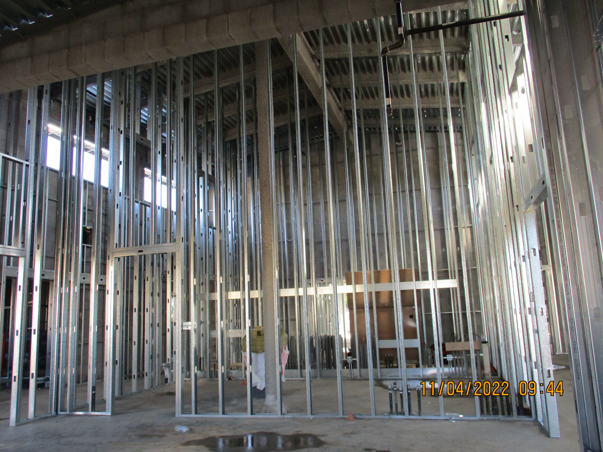 Metal stud framing in a building under construction, with exposed columns and beams, dated 11/04/2022.