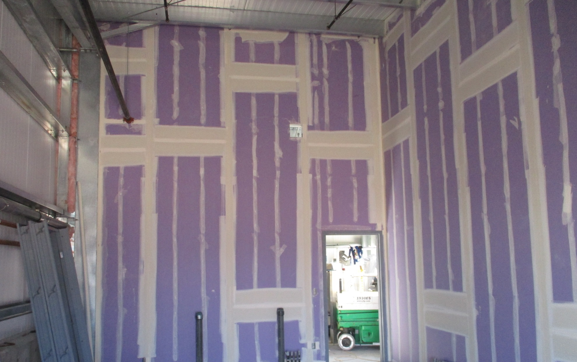 A room under construction with insulation and drywall installation in progress.