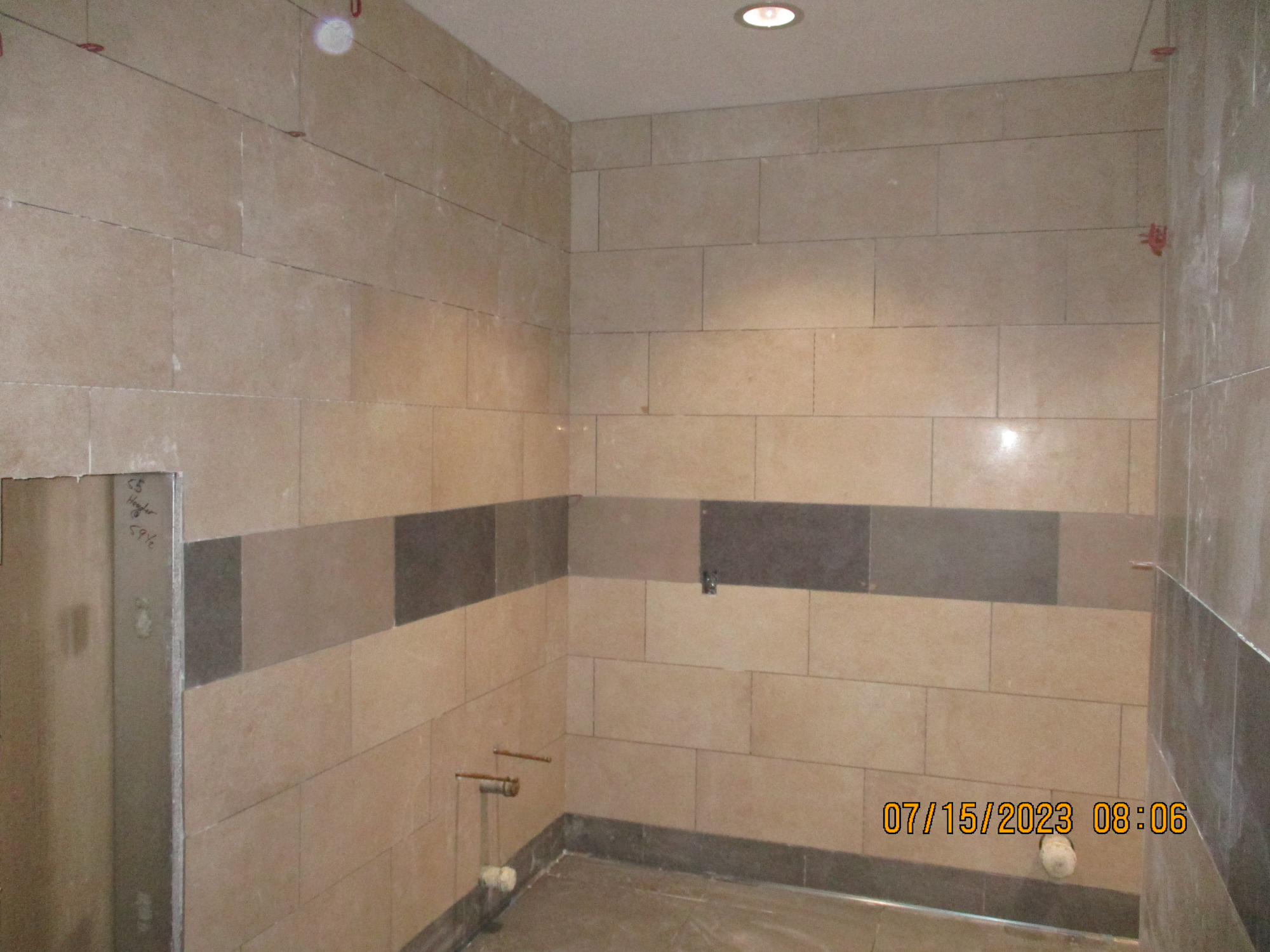 An unfinished tiled shower area with exposed plumbing and incomplete wall surfaces.
