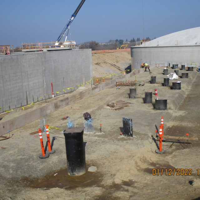 Construction site with concrete walls, exposed rebar, equipment, and workers.