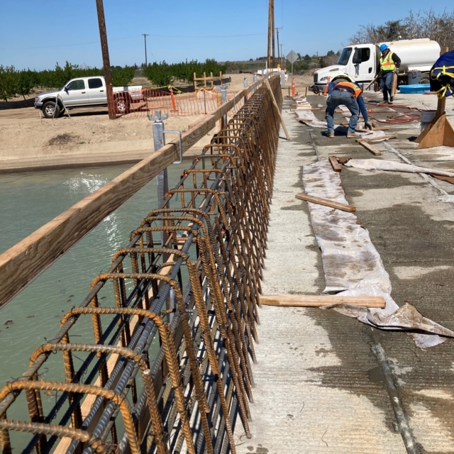 Construction site with rebar framework and workers pouring concrete.