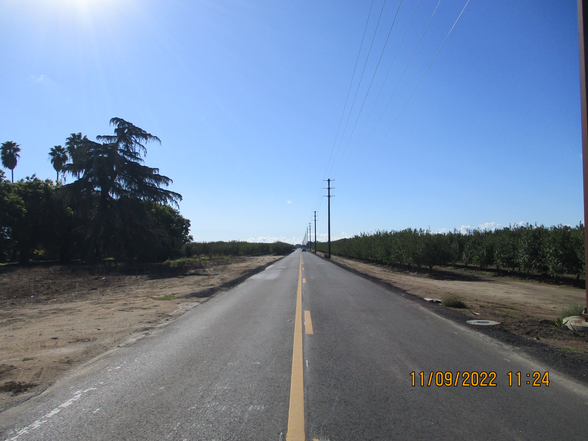 A rural road with power lines, trees, and clear blue skies. Date stamp: "11/09/2022 11:24"