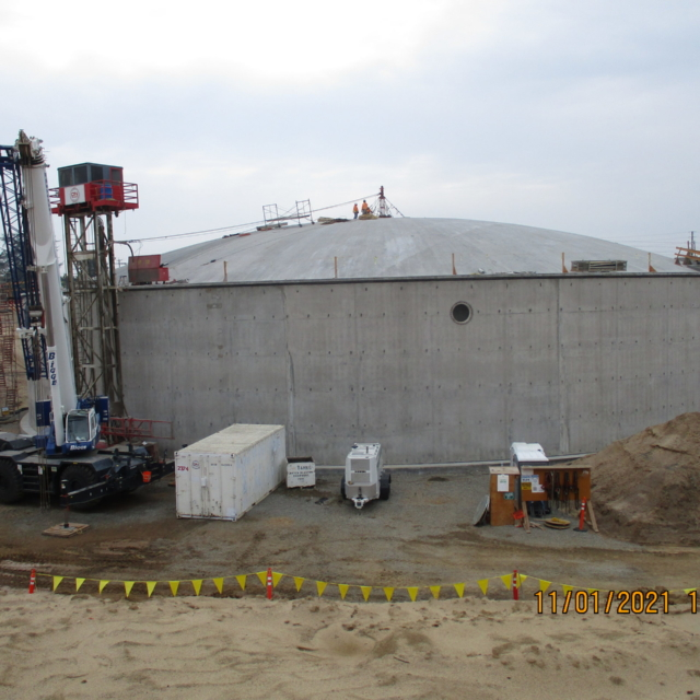 A construction site with a large concrete structure, equipment, and workers on top.