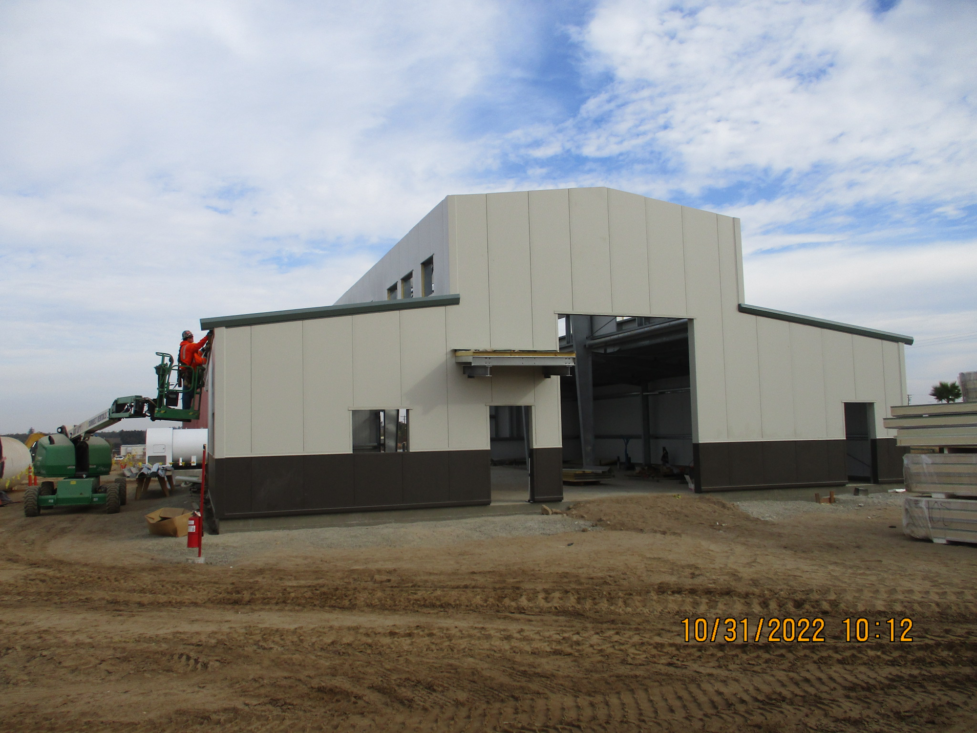 Industrial building under construction with a worker on a cherry picker.