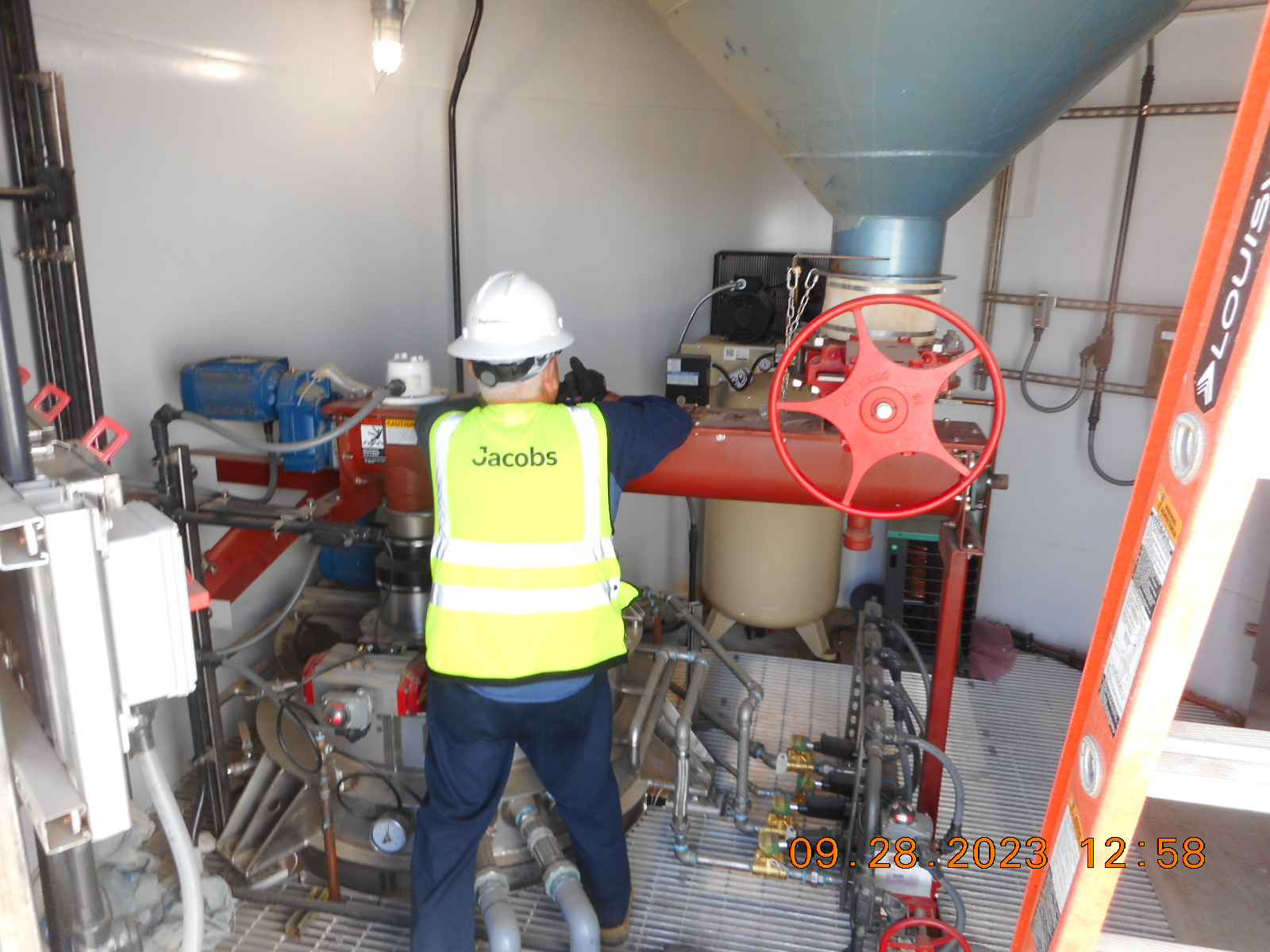 Person in hard hat operating machinery within an industrial setting.
