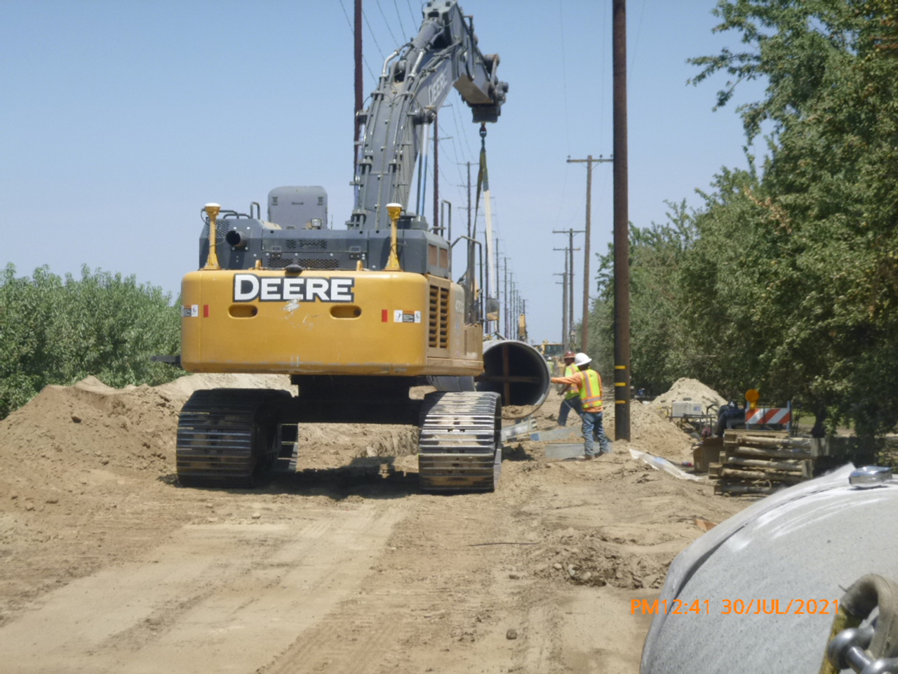 A construction site with an excavator and a worker wearing a high-visibility vest.