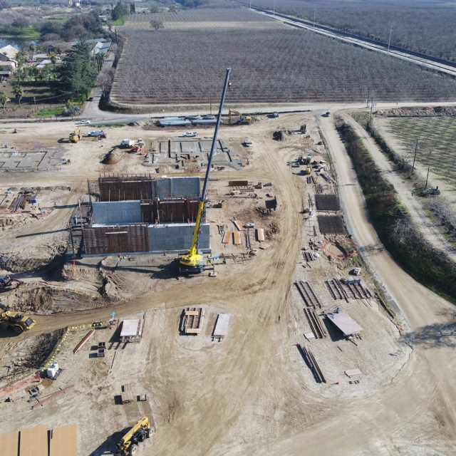 Aerial view of a construction site with a crane, vehicles, and groundwork for a building.