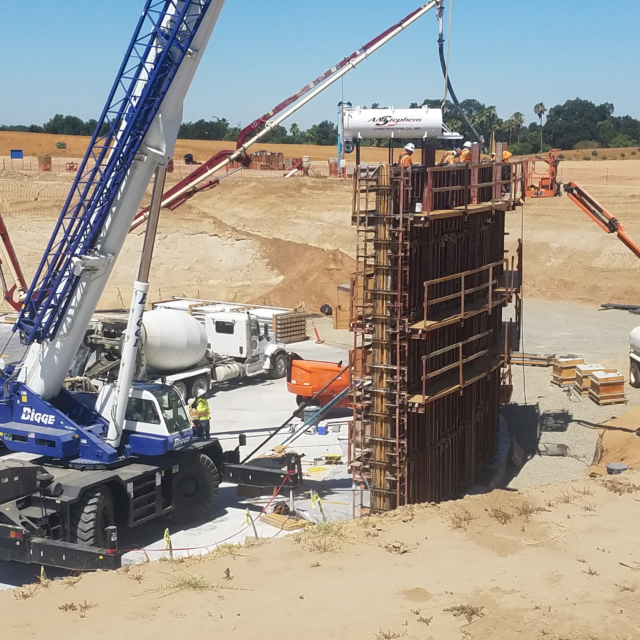 Construction site with cranes, concrete pouring and a large formwork setup.