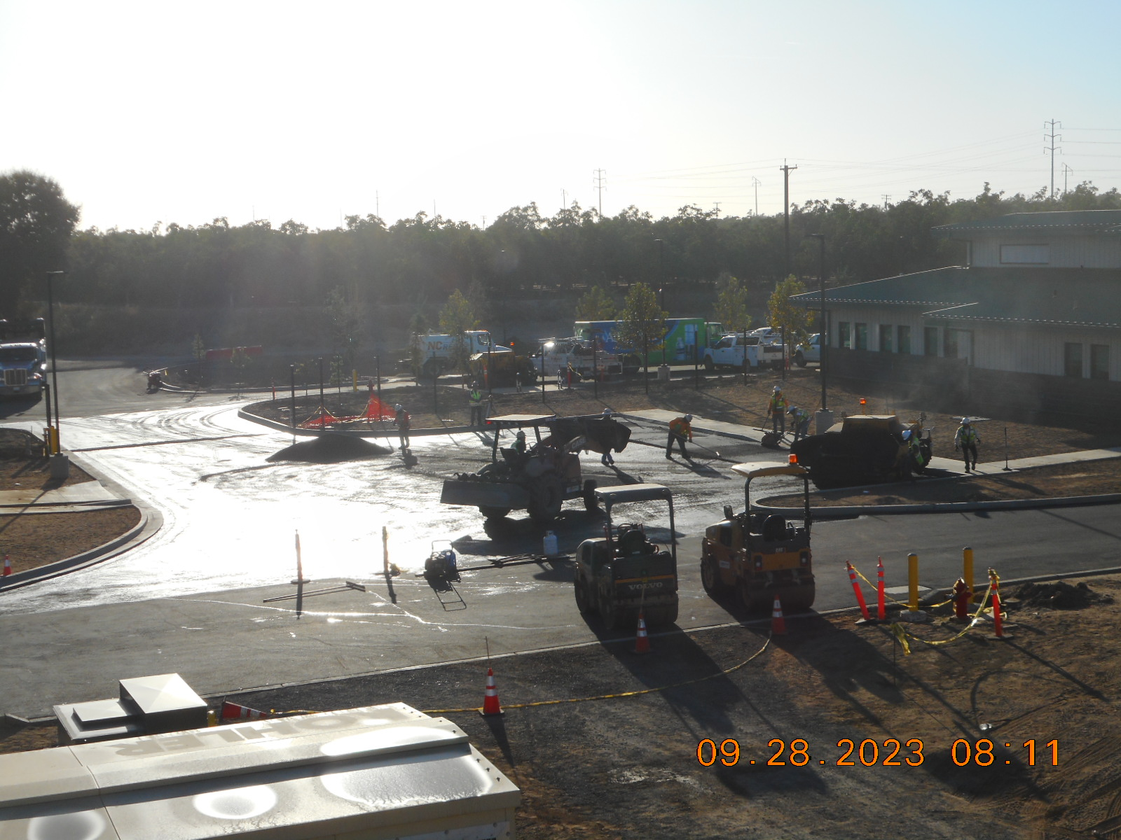 Construction site with workers and machinery paving a road, with timestamp "09.28.2023 08:11".