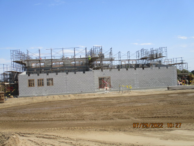 Construction site with partially completed building and scaffolding under a clear sky.