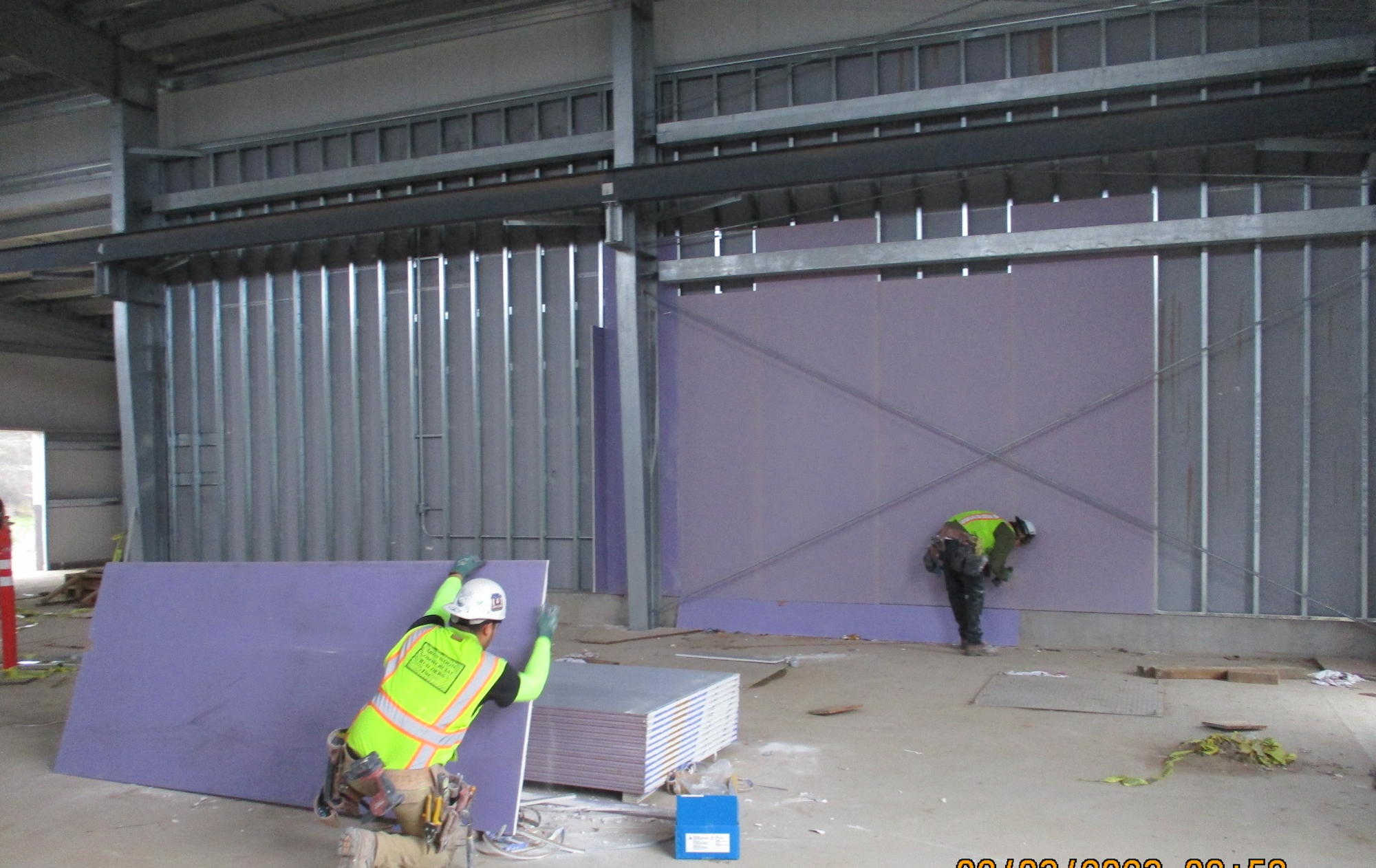 Construction workers installing drywall in a building under construction.