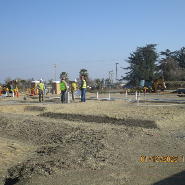 Construction site with workers, machinery, and marked foundations.