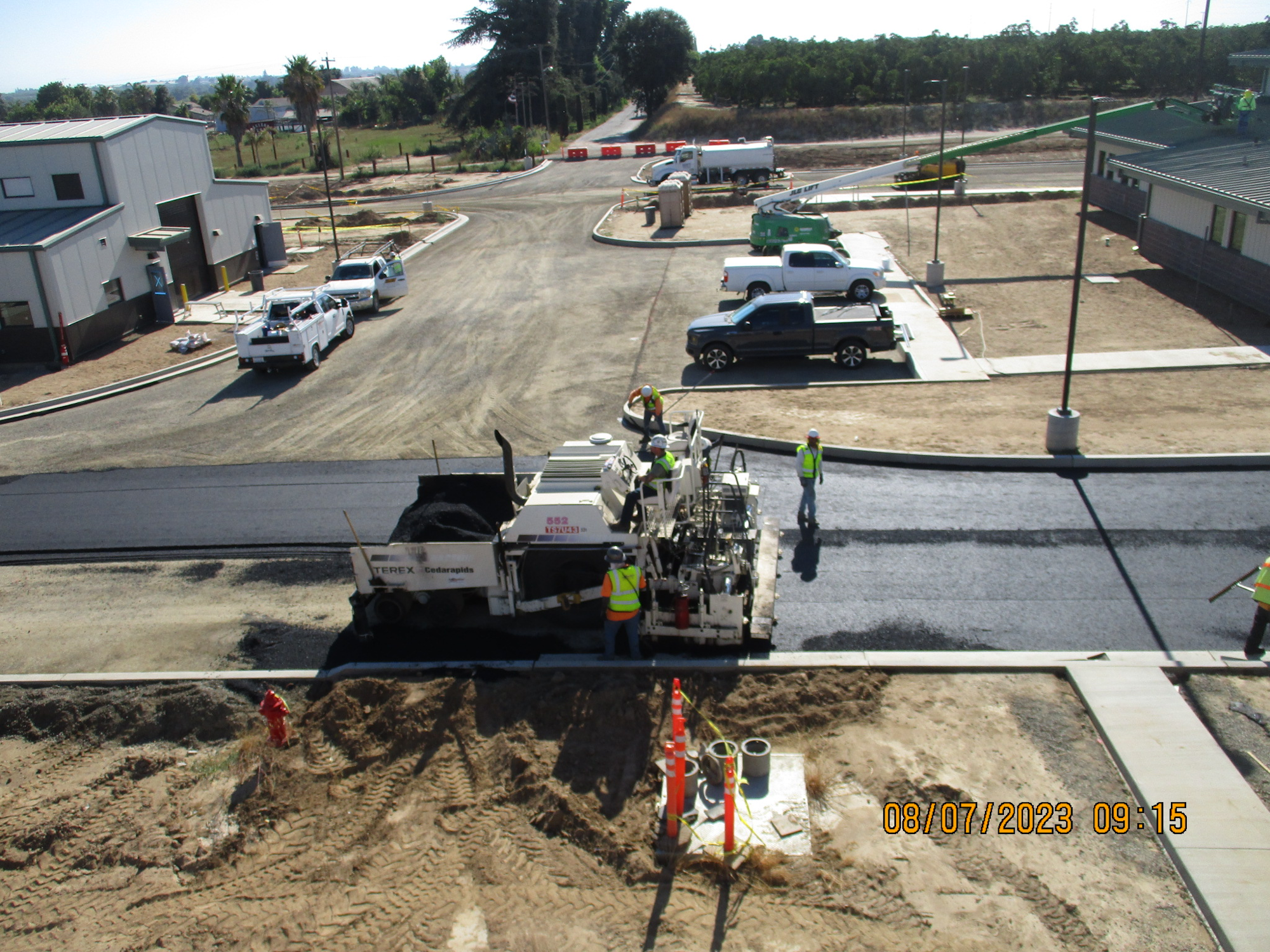 Road construction site with workers, vehicles, and machinery paving.