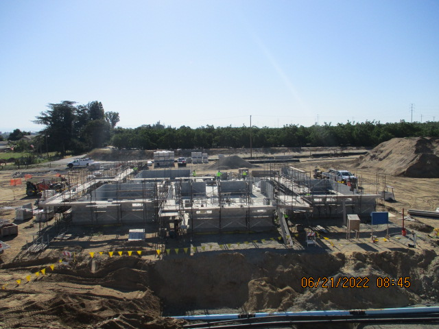 Construction site with foundation work, workers, equipment, and excavated dirt.