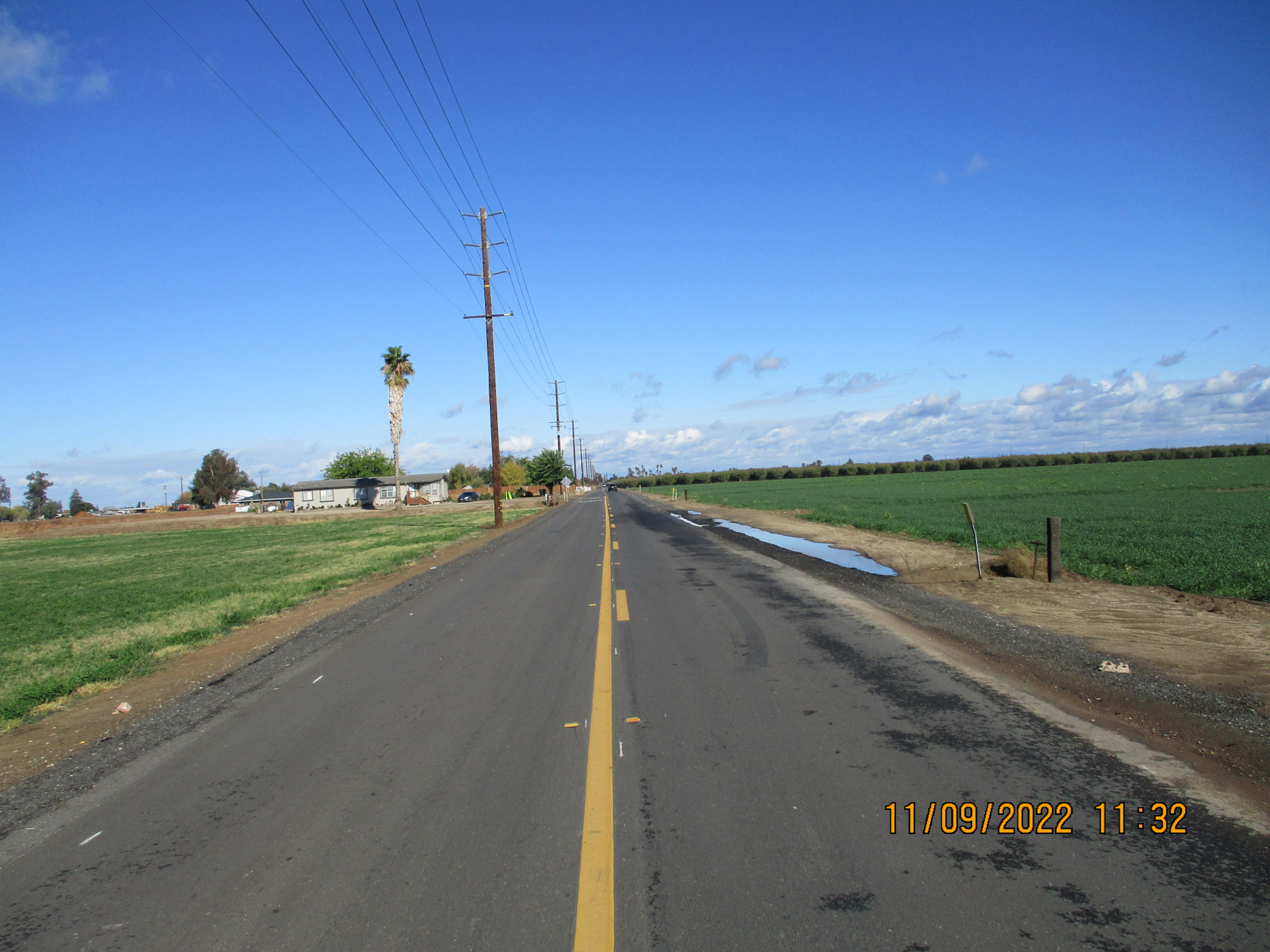 Country road with power lines, a clear sky, and fields on either side. Timestamped 11/09/2022, 11:32.