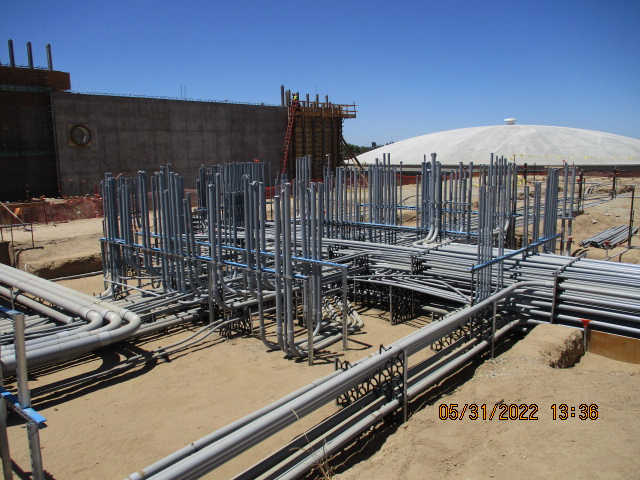 Construction site with metal frameworks and pipelines on the ground.