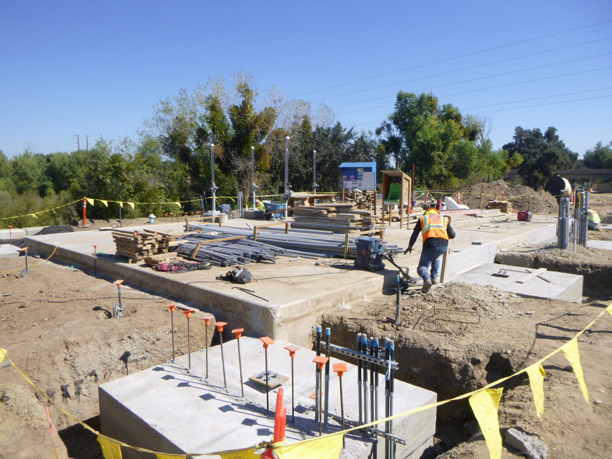 Construction site with foundations, building materials, and a worker.