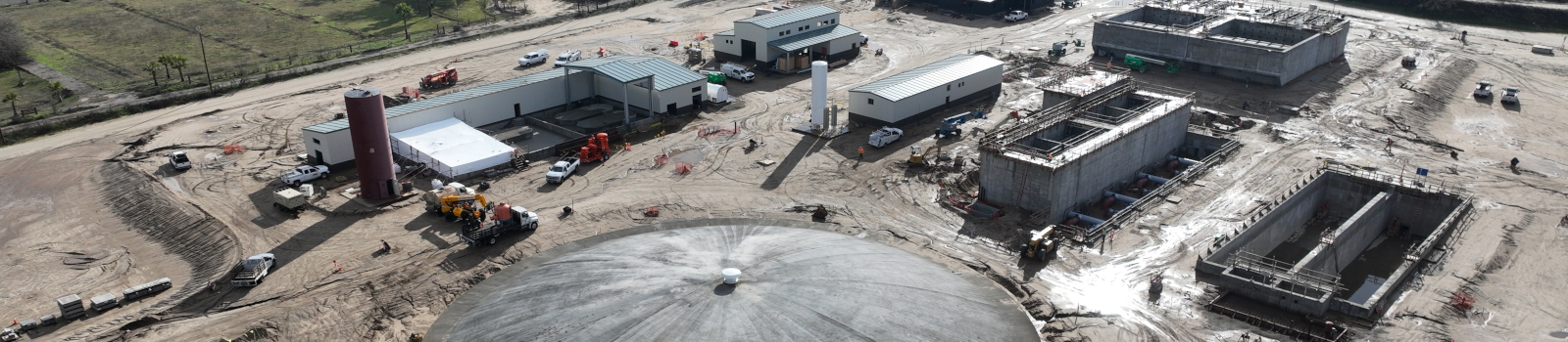 Aerial view of an industrial construction site with buildings, vehicles, and equipment.