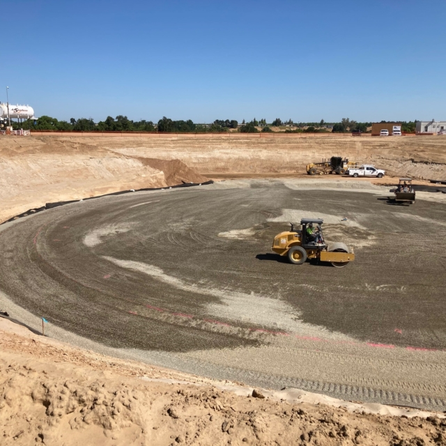 Construction site with excavation and compaction machinery at work.