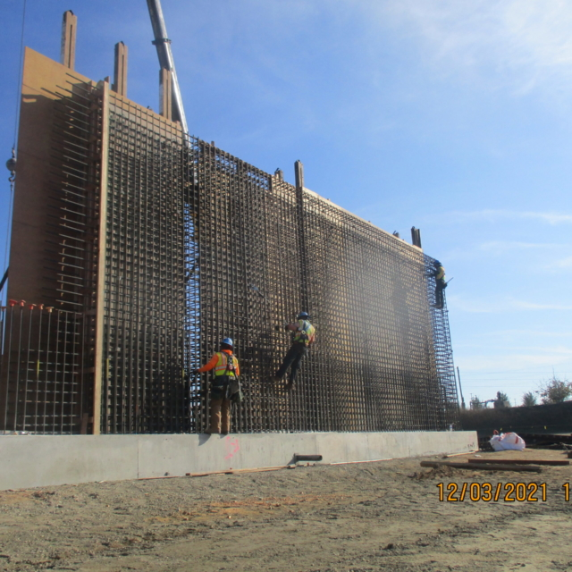 Construction site with large rebar structure and workers.