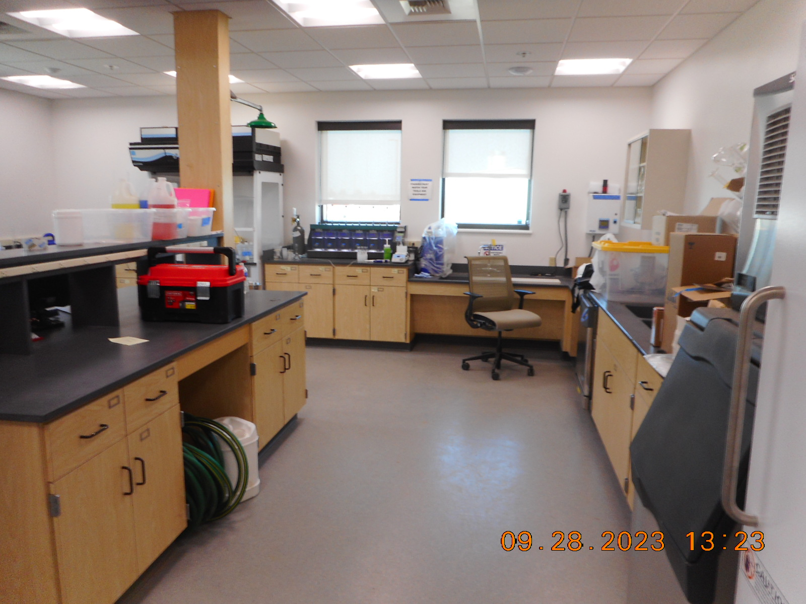 A laboratory with benches, cabinets, equipment, and a rolling chair.