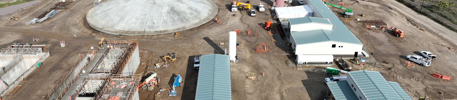 An aerial view of a construction site with buildings, vehicles, and workers.