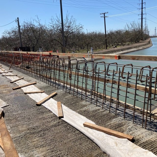 Construction site with rebar framework, wooden planks, and burlap, possibly a concrete foundation being prepared.