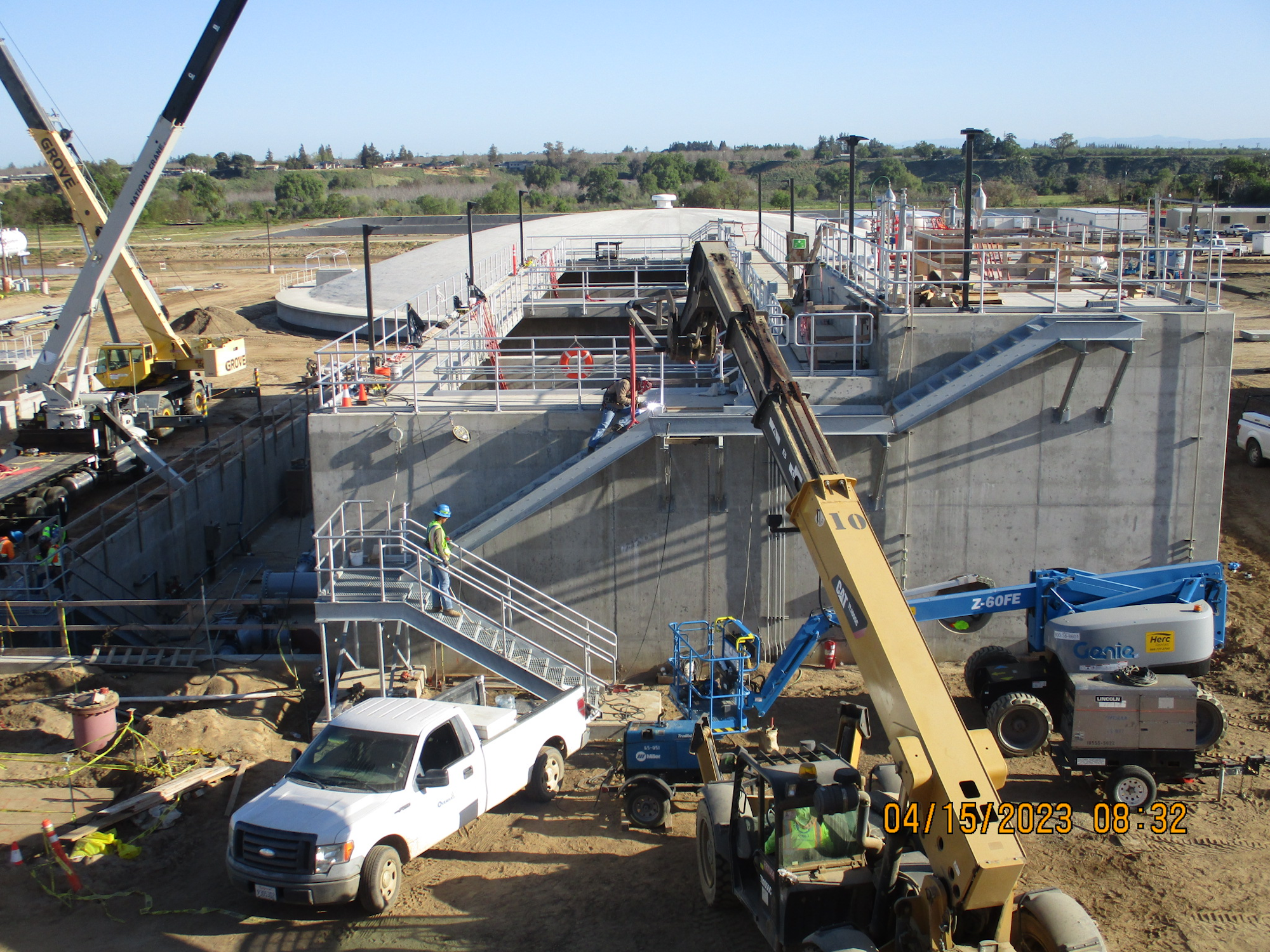 Construction site with workers, heavy machinery, and concrete structures.