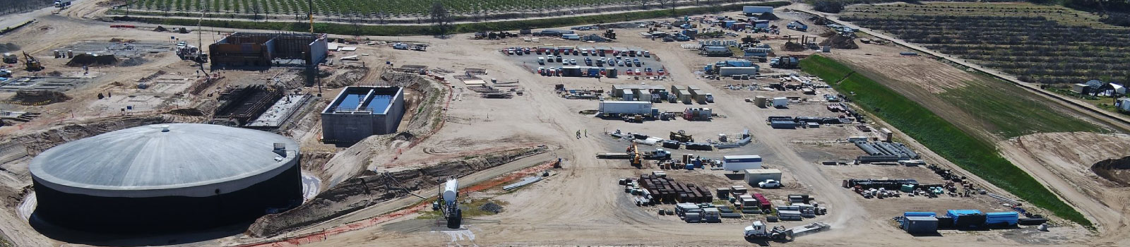 Aerial view of a construction site with equipment, vehicles, and a large circular structure.