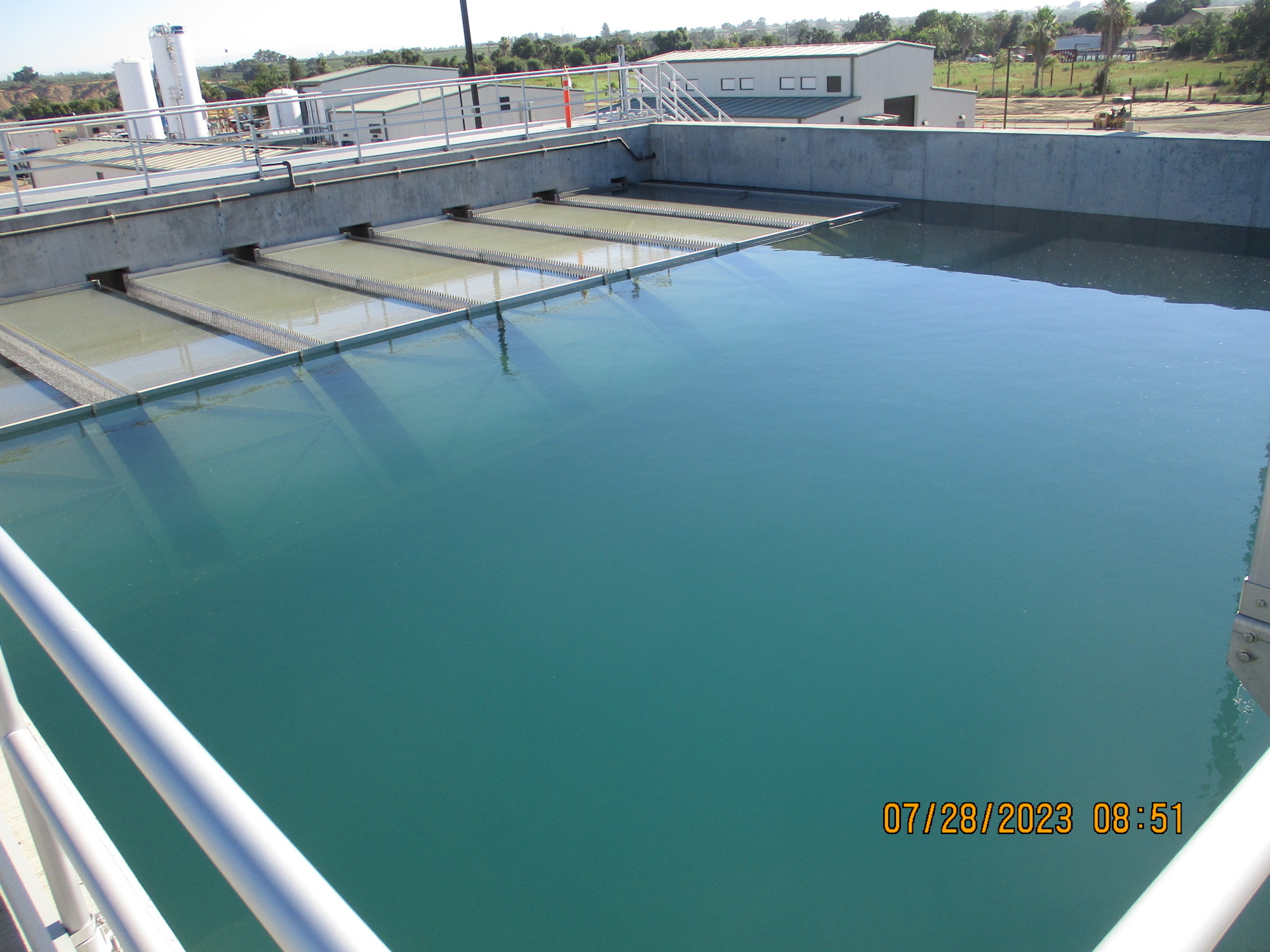 A water treatment plant with sedimentation tanks under a clear sky.