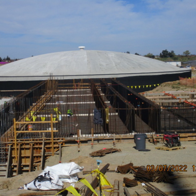 Construction site with a large dome structure and workers.