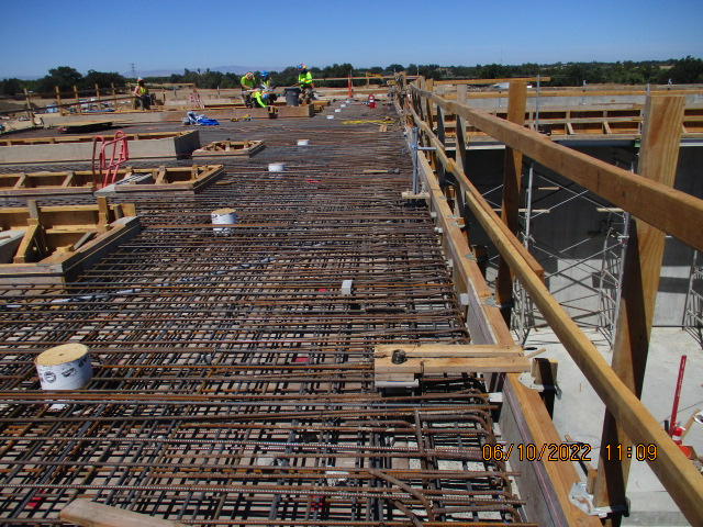 Construction site with rebar framework and workers in the background.