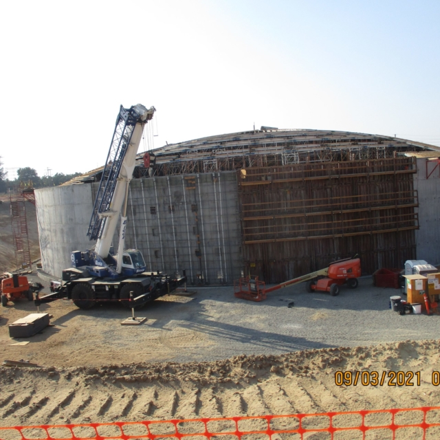 Construction site with a crane, scaffold, and concrete structure.