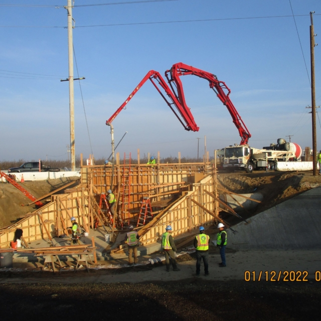 Construction site with workers and a concrete pump truck.