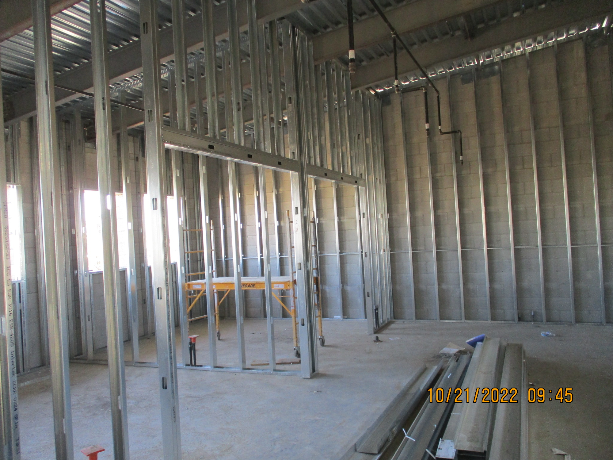 An unfinished interior space with metal stud framing, concrete floors, and walls.